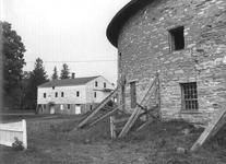 SA0741.19 - Photo of section of round barn, with tan house in background.